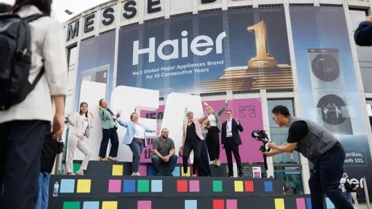 Menschen jubeln auf einer Bühne vor dem Eingang der Messe Berlin, Fotograf macht ein Bild.