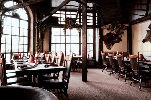 Gemütliches, rustikales Restaurant mit Holztischen und großen Fenstern.
