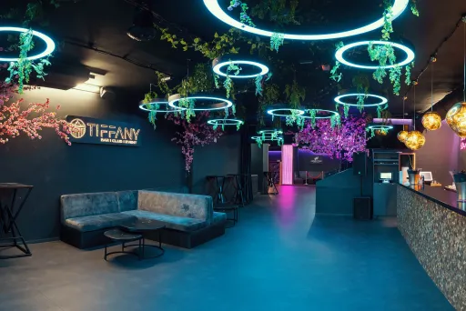 Modern eingerichtete Bar mit Neonlichtern, Pflanzen und gemütlichen Sitzbereichen.