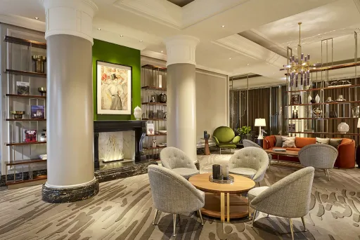 Modern eingerichtete Hotellobby mit Kamin, Sesseln, Sofas und großen Fenstern.