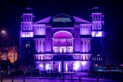Beleuchtetes Theatergebäude bei Nacht in violetten und blauen Farbtönen