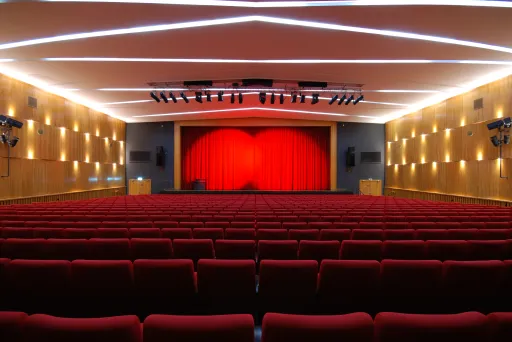 Leerer Theatersaal mit roten Sitzen und rotem Vorhang auf der Bühne
