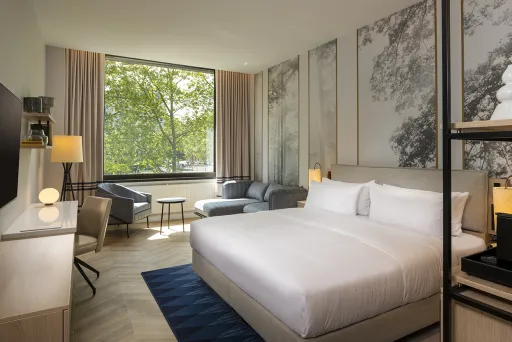 Modernes Hotelzimmer mit Doppelbett, großem Fenster und gemütlicher Sitzecke.