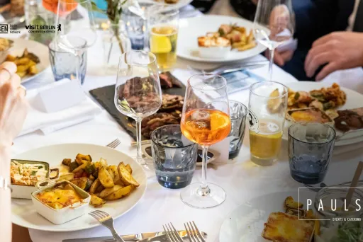 Festlich gedeckter Tisch mit verschiedenen Speisen und Getränken, mehrere Personen essen.