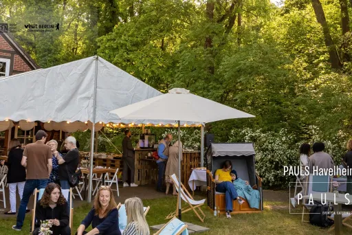 Gartenfest mit weißen Zelten, Menschen plaudern entspannt im Grünen.