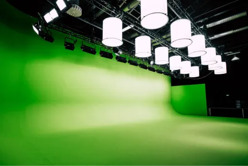 Studio mit grünem Greenscreen, vielen Lampen und schwarzer Decke.