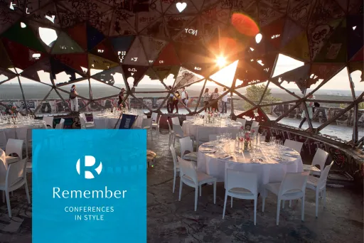 Gedeckte runde Tische mit weißen Stühlen unter Kuppel mit Sonnenuntergang im Hintergrund; im Vordergrund ein  blaues Quadrat mit weißen "R" und  und Text "Remember Conferences in Style"