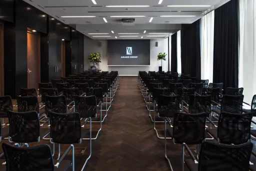 Leerer Konferenzraum mit Reihen schwarzer Stühle und Leinwand vorne