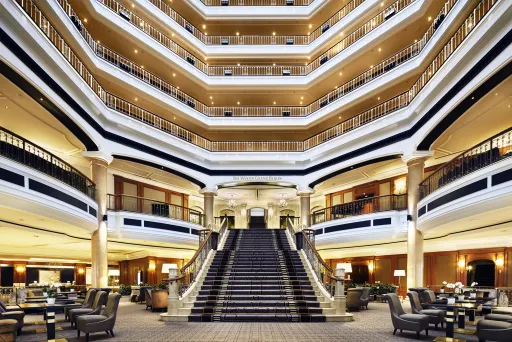 Großzügige Hotellobby mit breiter Treppe und mehreren Balkonetagen.