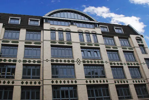 Gekacheltes, 5-stöckiges Gebäude, blauer Himmel mit weißen Wolken
