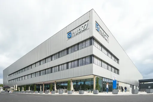 Modernes Bürogebäude mit TRUMPF-Logo und Glasfassade an einem bewölkten Tag.