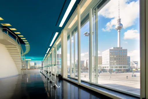 Blick durch große Fenster auf den Berliner Fernsehturm bei sonnigem Wetter.
