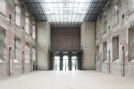 Große, leere Industriehalle mit Backsteinwänden und Glasdach