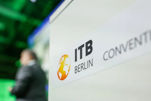 ITB Berlin Convention Logo auf einem Schild, Person unscharf im Hintergrund.