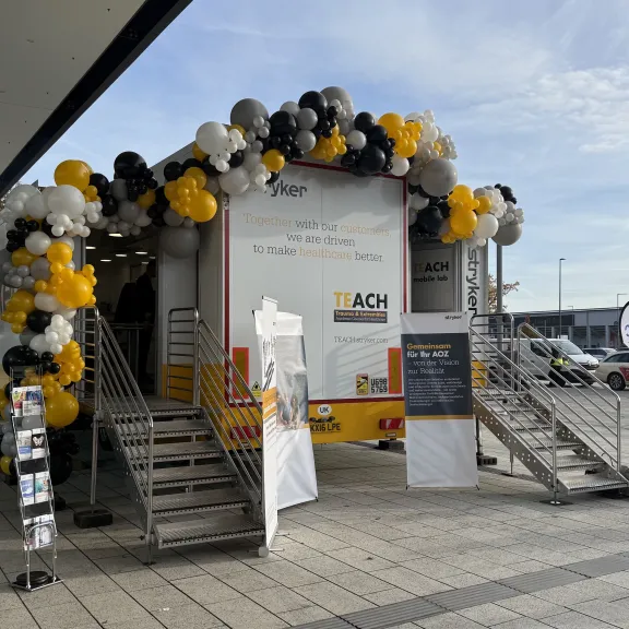 Mobiler Ausstellungswagen mit schwarzen, gelben und weißen Luftballons dekoriert.