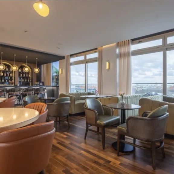 Modernes Café mit großen Fenstern, gemütlichen Sitzmöbeln und Barbereich bei Tageslicht.