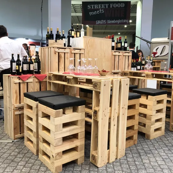 Holztische und Hocker aus Paletten mit Weinflaschen in einer modernen Bar.