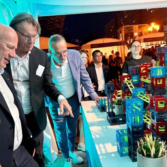 Der Regierende Bürgermeister von Berlin betrachtet bunte Modelle auf einem Tisch beim Hoffest