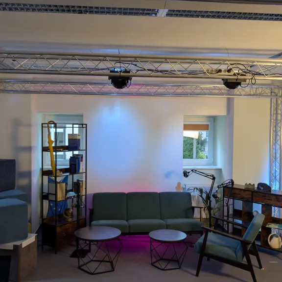 Modernes Wohnzimmer mit Sofa, Sesseln, Regalen und Beleuchtung, gemütlich eingerichtet.