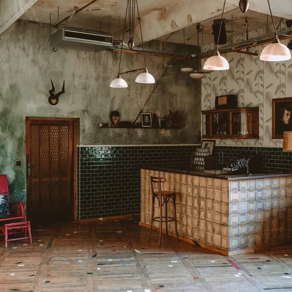 Gemütliche Vintage-Bar mit Holzboden, grüner Wand und Retro-Möbeln.