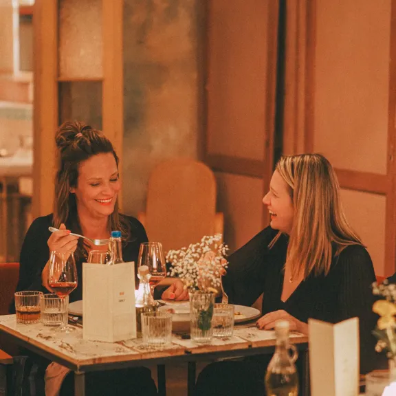 Zwei Frauen unterhalten sich in gemütlichem Restaurant bei Kerzenschein.