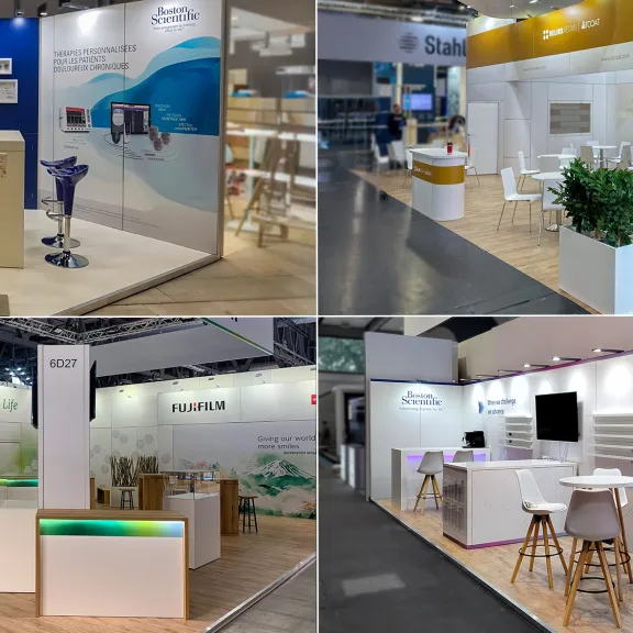 Vier moderne Messestände mit Tischen, Stühlen und Bildschirmen auf einer Messe.