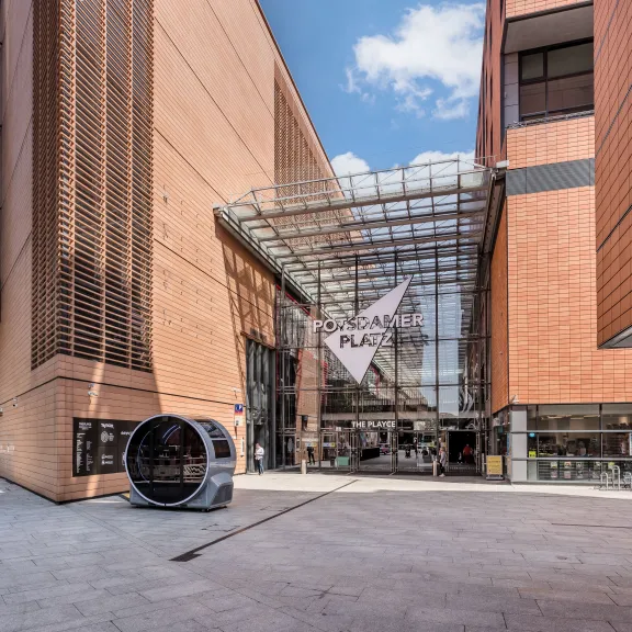 Modernes Gebäude mit Glasfassade, Eingang mit Vitra-Logo bei sonnigem Wetter.