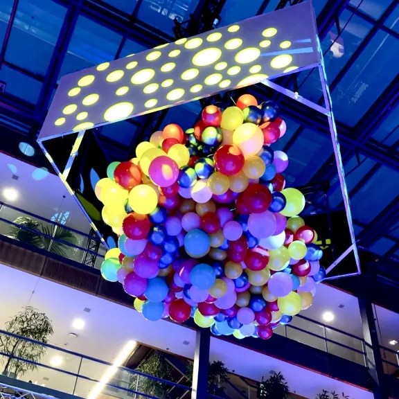 Bunte Ballons unter einer Decke mit Lichtpunkten in einem modernen Gebäude.