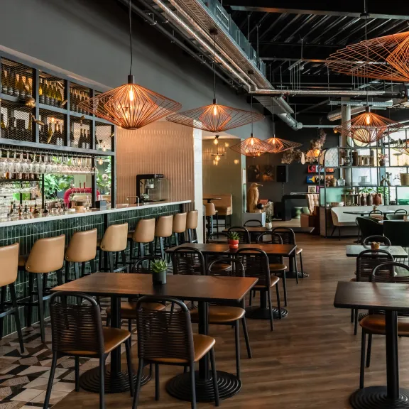 Modernes Restaurant mit Bar, Holztischen und stilvoller Beleuchtung