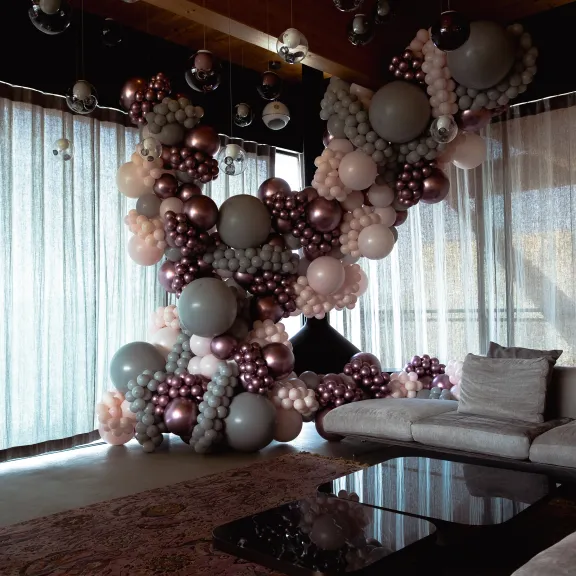 Große Ballon-Dekoration im modernen Wohnzimmer mit grauen Sofas und Glastisch.