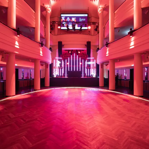 Leerer Ballsaal mit rotem Licht und Bühne im Hintergrund