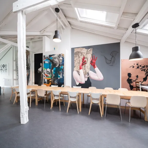 Heller Konferenzraum mit langem Holztisch, modernen Stühlen und Wandkunst.