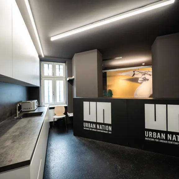 Moderne Küche mit schwarzer Theke und weißen Schränken, Urban Nation Logo sichtbar
