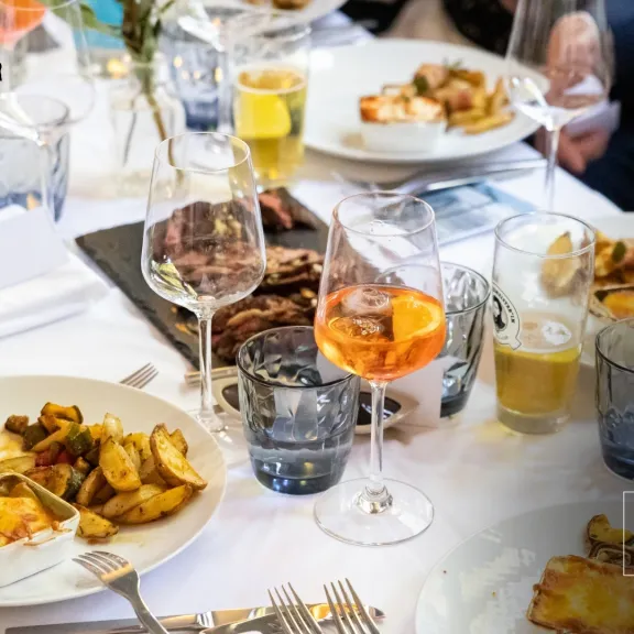 Festlich gedeckter Tisch mit verschiedenen Speisen und Getränken, mehrere Personen essen.