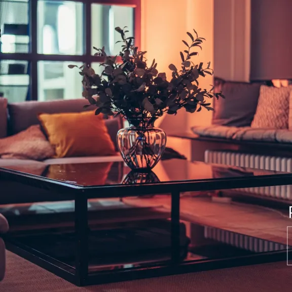 Gemütliche Lounge mit Sofas, vielen Kissen und einem Glastisch mit Vase.