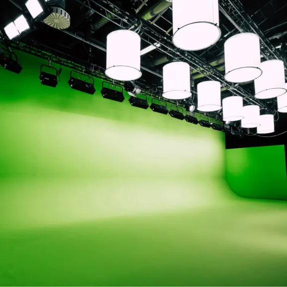 Studio mit grünem Greenscreen, vielen Lampen und schwarzer Decke.