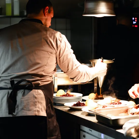 Zwei Köche bereiten Essen in einer professionellen Restaurantküche zu.