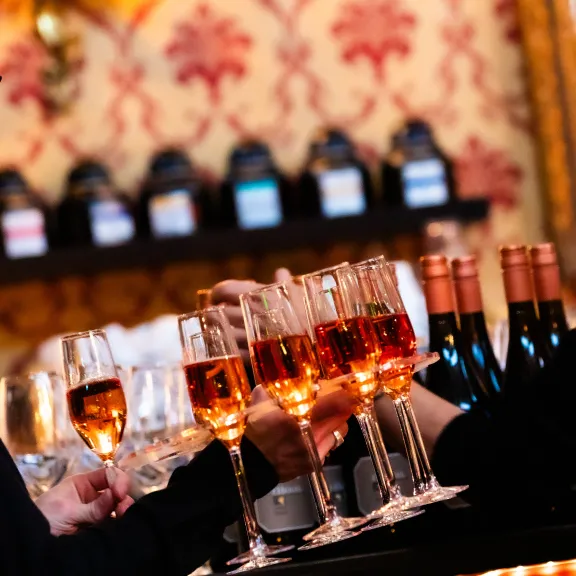 Zwei Personen an einer Bar mit mehreren Gläsern Roséwein und Weinflaschen.