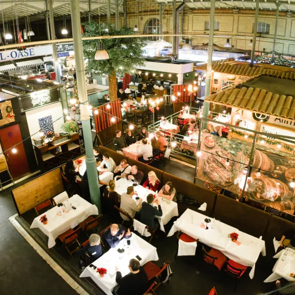 Großes, belebtes Restaurant mit festlich gedeckten Tischen und warmem Licht.