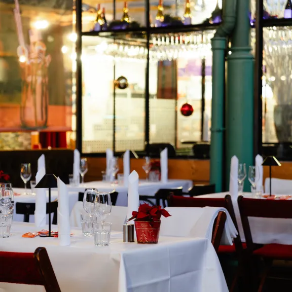 Festlich gedeckte Tische in einem eleganten Restaurant mit weißer Tischdecke.