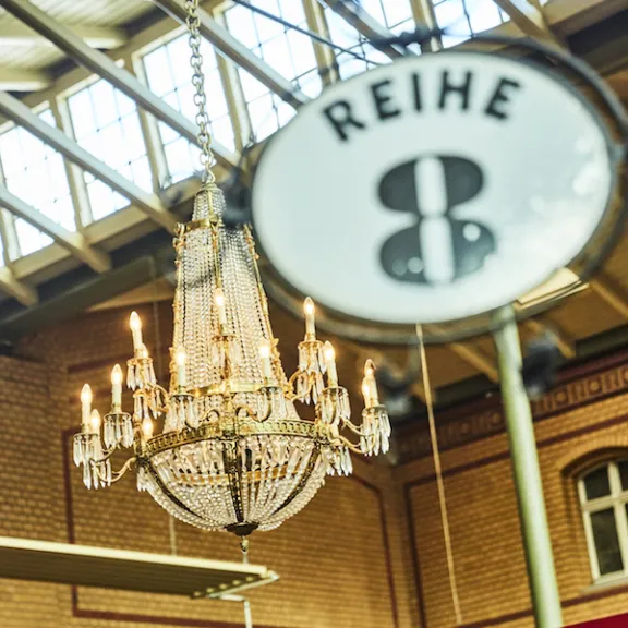 Kronleuchter in einer Halle mit Schild "Reihe 8" im Vordergrund.