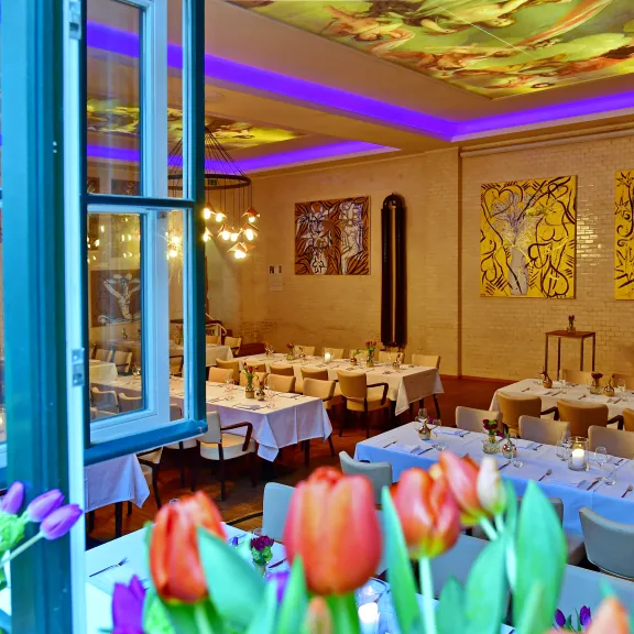 Elegant gedeckter Speisesaal mit Tulpen im Vordergrund und bunter Beleuchtung