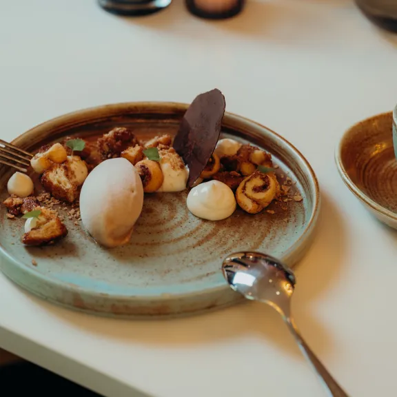 Dessert auf Keramikteller mit Eis, Creme und Kaffee auf weißem Tisch.
