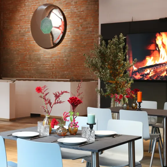 Modernes Restaurant mit gedeckten Tischen, Kaminfeuer und Backsteinwand.