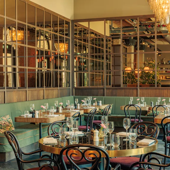 Elegant eingerichtetes Restaurant mit gedeckten Tischen und warmem Licht.