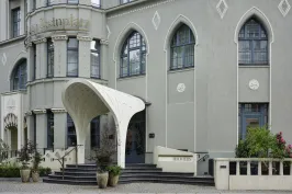 Hoteleingang mit modernem weißen Vordach, großen Fenstern und grauer Fassade