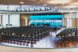 Moderner Veranstaltungssaal mit leeren Stuhlreihen und großer LED-Bühne.