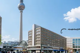 Berliner Fernsehturm und Gebäude am Alexanderplatz bei blauem Himmel mit weißen Wolken.