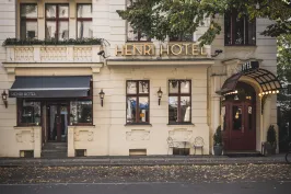 Helles Hotelgebäude mit rotem Eingang und goldener "Henri Hotel" Beschriftung.