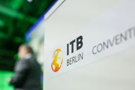 ITB Berlin Convention Logo auf einem Schild, Person unscharf im Hintergrund.